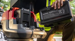 Close up showing the user inserting the battery into the battery lawn mower battery bay. 