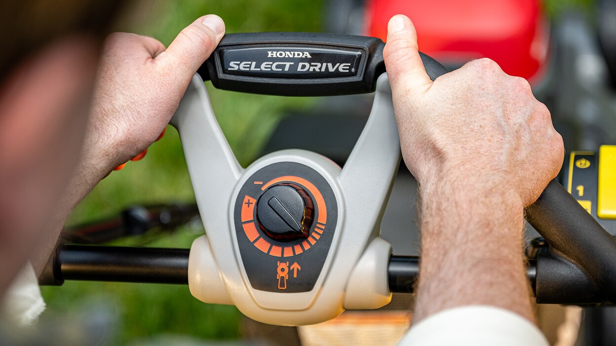 Close up of a person's hands holding the battery lawn mower handle.
