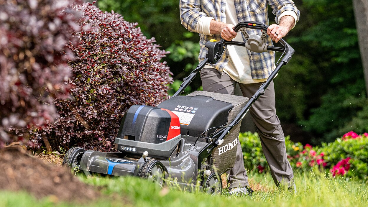 Person using a Honda Battery Lawn Mower to mow the lawn. 