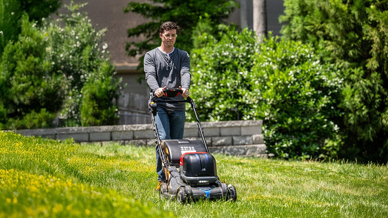 Person using a Honda Battery Lawn Mower to mow the lawn. 