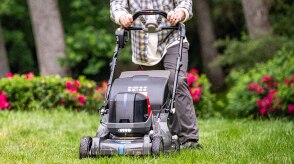 Person pushing a battery lawn mower to mow the lawn. 
