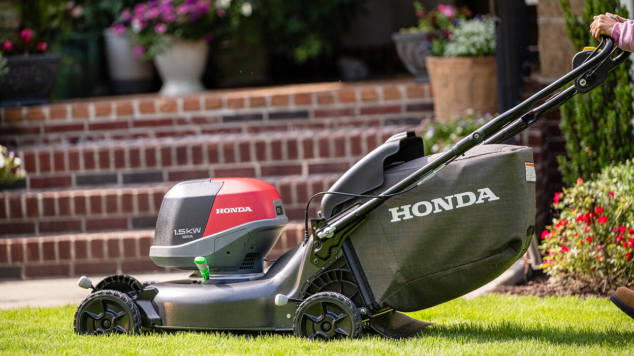 Close up of a battery lawn mower in action towards the left. 