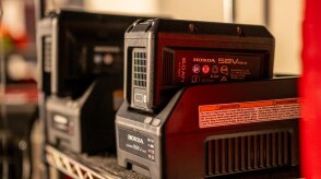 Two battery lawn mower batteries on their chargers in the garage. 