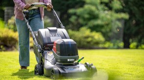 Person pushing a battery lawn mower to mow the lawn. 