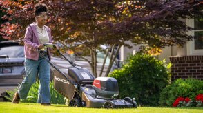 Person using a Honda Battery Lawn Mower to mow the lawn. 