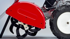 Gros plan latéral du motoculteur sur fond blanc, montrant l’arbre du rotor et les fourchons. 